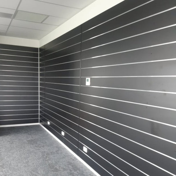 Room with black 150mm slatwall paneled walls and a grey floor.