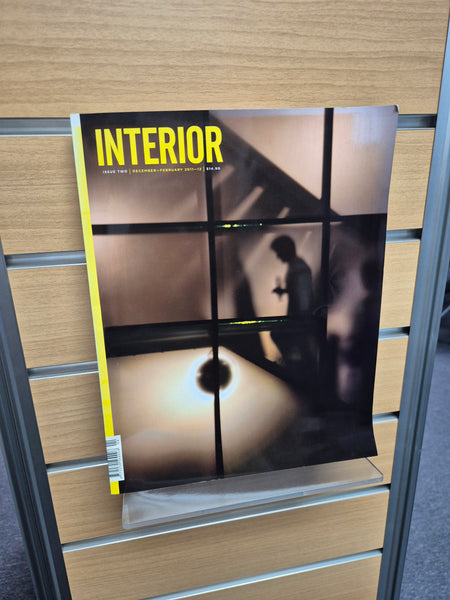 Book titled 'INTERIOR' on a clear display shelf mounted on slatwall 
