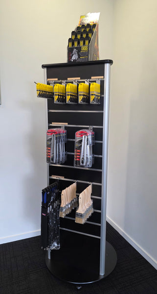 three sided Plankwall slatwall retail display stand in black displaying paint brushes in a showroom  
