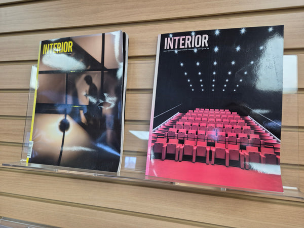 Two 'INTERIOR' books displayed on a clear display shelf 480mm mounted on a wooden slatwall display system.
