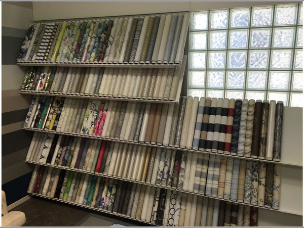 sloping metal shelves held with adjustable metal brackets displaying wallpaper rolls in a retail setting