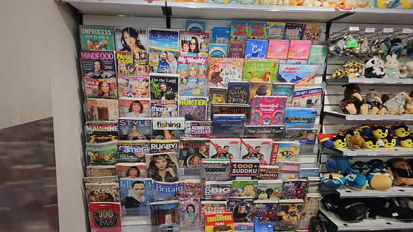 Calext modular magazine rack system installed on a retail slatwall panel with various magazines and toys in a shop setting