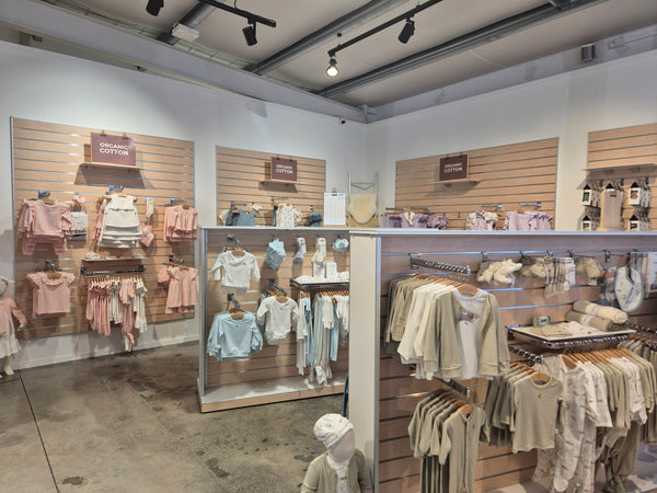 slatwall panels affixed to store walls and free standing display gondolas merchandised with kids clothes and accessories hung on brackets and on shelves.