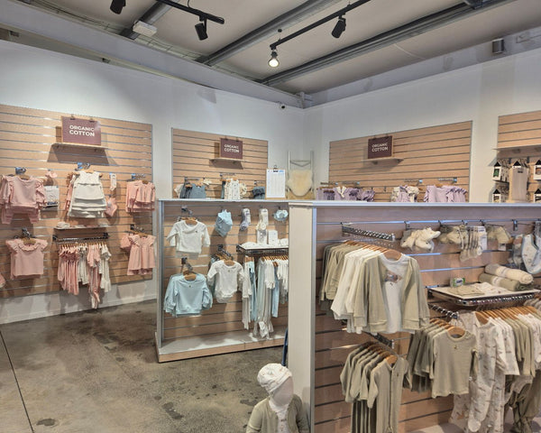 slatwall panels affixed to store walls and free standing display gondolas merchandised with kids clothes and accessories hung on brackets and on shelves.