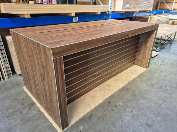 Large Plankwall electronics retail  display table in a dark wood finish in the factory