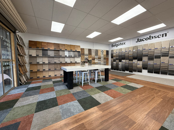 Flooring showroom displaying wood panels and carpet samples wall mounted on white slatwall panels.