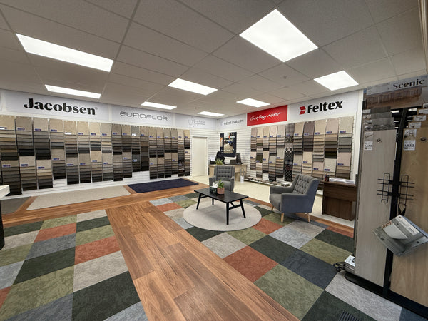 Interior of a flooring showroom with various carpet samples displayed walls mounted on white slatwall panels.
