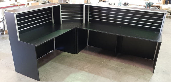 Plankwall L shaped large black reception desk in a factory setting