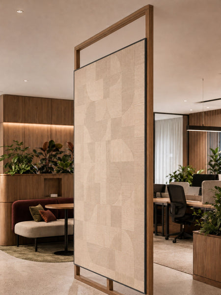 A tall modern room divider screen with a textured beige fabric panel capped with black MCLNCAP capping in a light wood frame, shown in a contemporary office lobby setting.