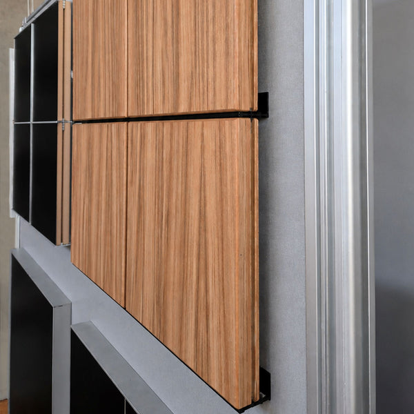 Close up of walnut MDF panels joined with black powder coated Stickman Aluminium wall fix butt joins attaching the panels to the backing grey board. 