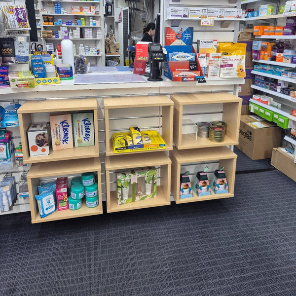 Pharmacy shelf with various products inside Plankwall's open display boxes on custom made slatwall retail countertop