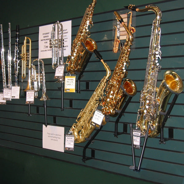 Gold saxophones on 75mm pitch slatwall  display against a green wall with price tags.