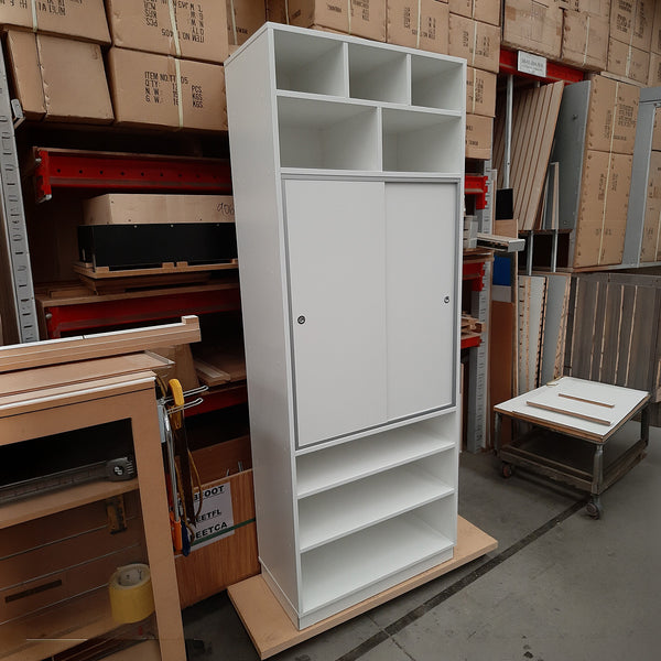 White storage cabinet with sliding door in a warehouse setting