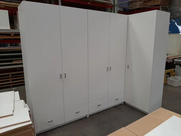 Plankwall custom storage lockers and wardrobe with drawers underneath in white in an L shape in a factory setting.