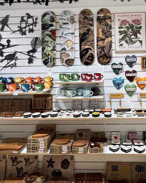 Plankwall White 100mm slatwall with shelving and a hung display of decorative items including mugs, wooden signs, and art.