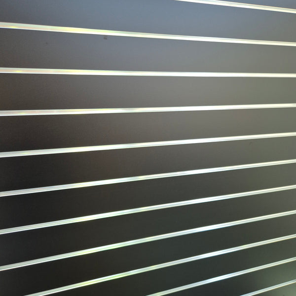 Close-up of a black slatwall surface with aluminium inserts