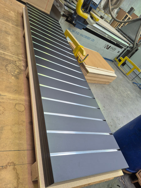 100mm slatwall panel with aluminium inserts shown stacked in the factory.