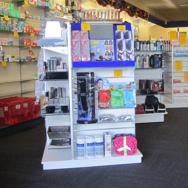 Plankwall freestanding four-sided display unit with slatwall panels on all sides displaying retail items in a pharmacy