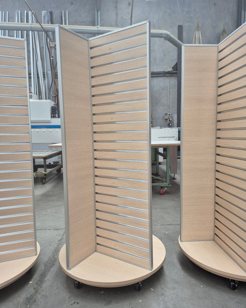 Plankwall four sided rotating retail display units x3 in perfect oak melamine slatwall with aluminium edging in a factory setting