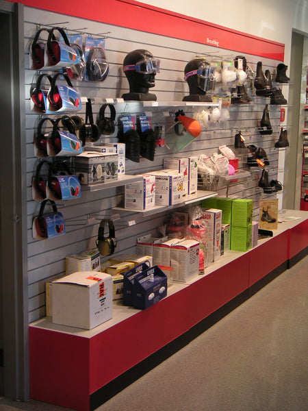 Display of safety equipment including headsets and boxes on a red and gray 100mm slatwall wall.