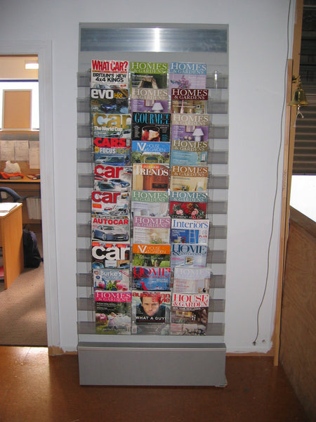 Calext magazine rack with various magazines displayed against a white wall.
