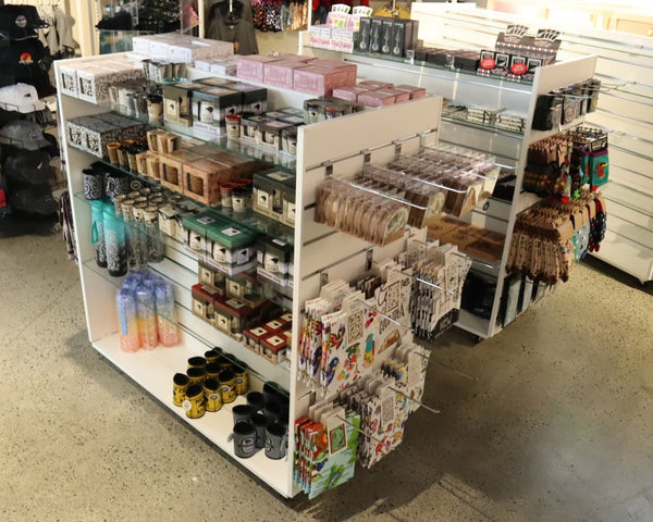 Plankwall slatwall display gondola lightweight with glass shelves in white merchandised with tourist products in a retail setting photographed  from above