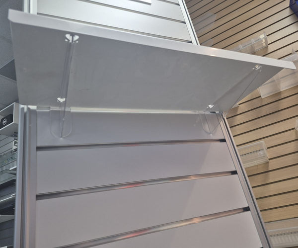 Flat metal retail shelf mounted on slatwall using clear polycarbonate flat shelf brackets, clean modular display solution by Plankwall.