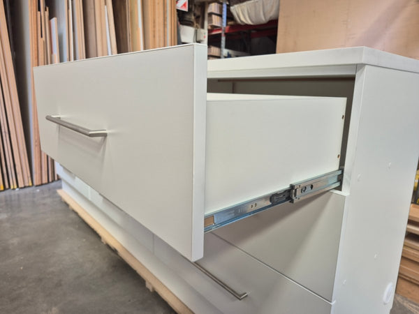 White Plankwall cabinet with a drawer pulled out, showing internal components, in a workshop setting.