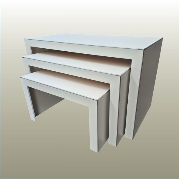 Set of three white nesting display tables on a beige background