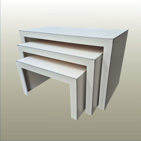 Set of three white nesting display tables on a beige background