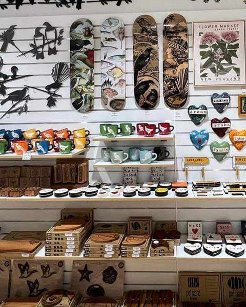 Plankwall White 100mm slatwall with shelving and a hung display of decorative items including mugs, wooden signs, and art.