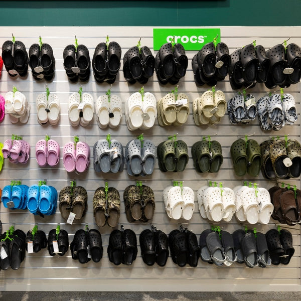 Display of Crocs shoes in various colors and styles mounted on a Plankwall slatwall Retail display wall panel.