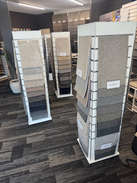 Display of various textured rugs on a Plankwall slimline box tower slatwall retail display stand in a store setting.