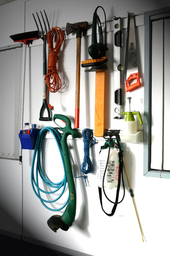 Garden tools and equipment hanging on a wall-mounted Plankwall Utility plank storage system