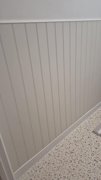 W Groove Dado panel wall with a white baseboard and speckled floor.
