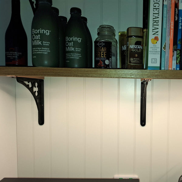 Shelf with bottles and books against a white W Grooved paneled wall.