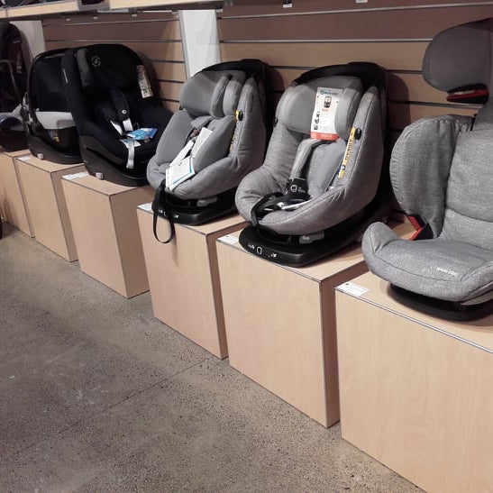 Row of gray car seats on display on blonde wood finish retail display cubes