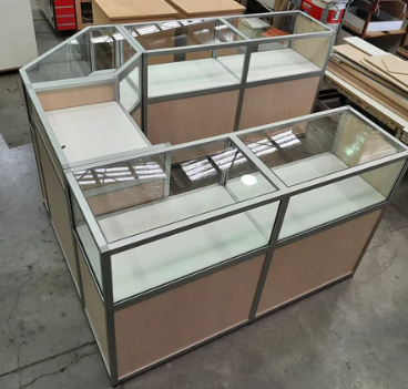 large Plankwall three sided retail counter with glass display cases and aluminium detailing in a factory setting