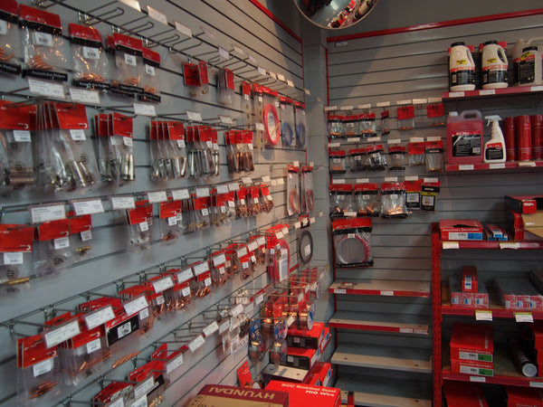 Grey 100mm slatwall panels with red trim lined wtih shelves with automotive parts and tools in a store setting