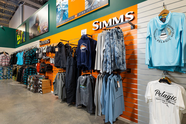 Plankwall slatwall wall panels in custom orange and washed oak in a retail store fitout shown displaying clothing and other apparel merchandise.
