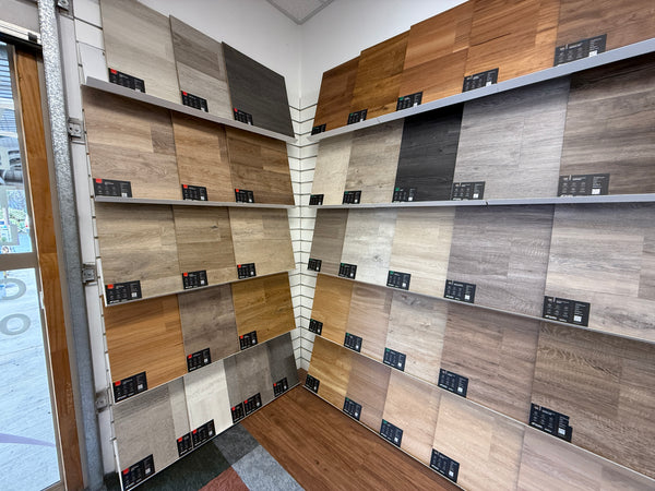 Display of wooden panel samples on white sloping shelves mounted on slatwall in a showroom setting