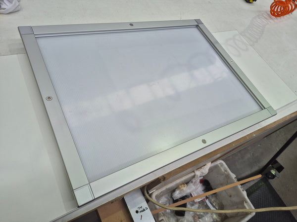 Photo of a Plankwall lockable aluminium snap frame for signs and posters shown on a workbench