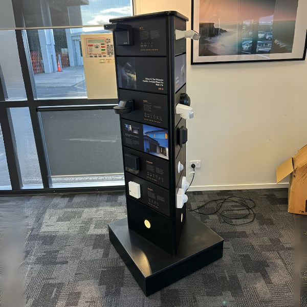 Plankwall 3-sided rotating floor display stand in custom black with light fixtures in a showroom side view
