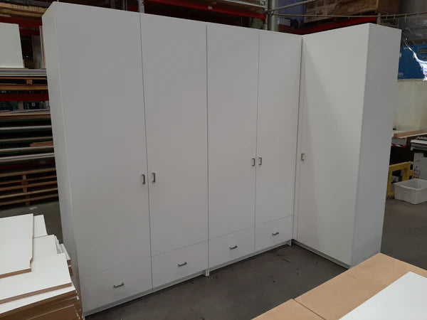 Plankwall custom storage lockers and wardrobe with drawers underneath in white in an L shape in a factory setting.