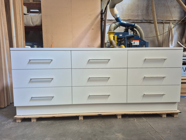 Plankwall white cupboard unit with 9 drawers in a factory setting