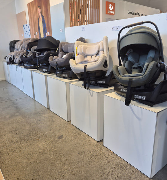 Multiple baby buggies merchandised on white display cubes in a row in a retail store.