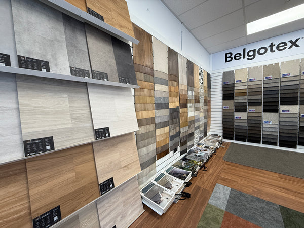 Display of flooring samples on 60 degree sloping shelves attached to slatwall in a showroom.