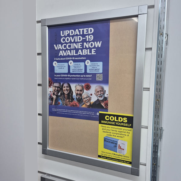 Vaccine information poster in Plankwall Poster Snap Frame on split rail mount on a bulletin board with a colds immunization flyer below.