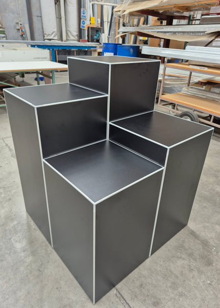 Plankwall retail display cubes in black shown stacked together in a factory setting