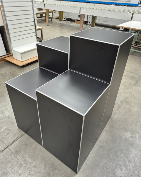 Set of 4 Plankwall cube retail display stands in black showing top surface area in a factory setting